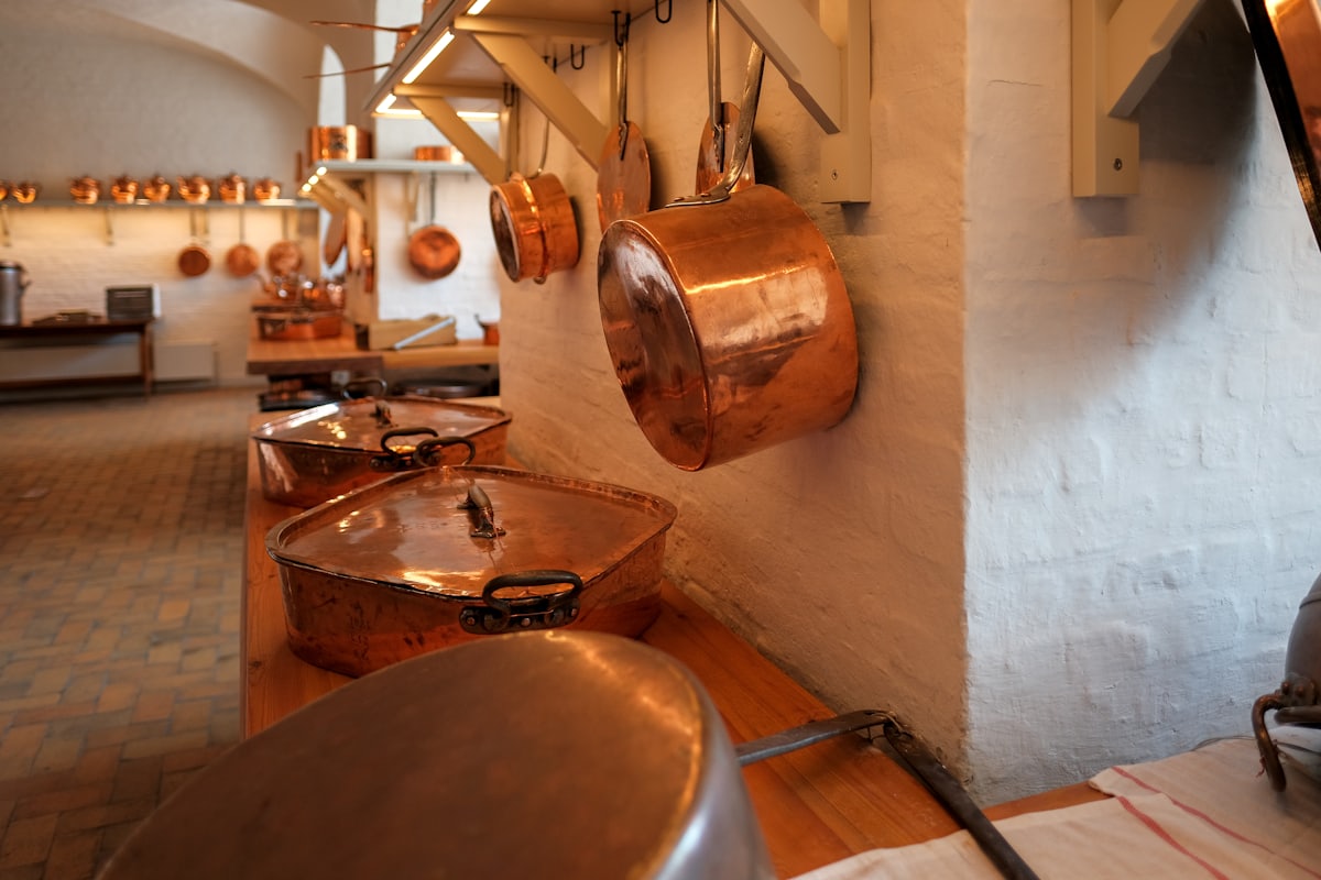 A batterie of copper pans hanging in a whitewashed vaulted kitchen