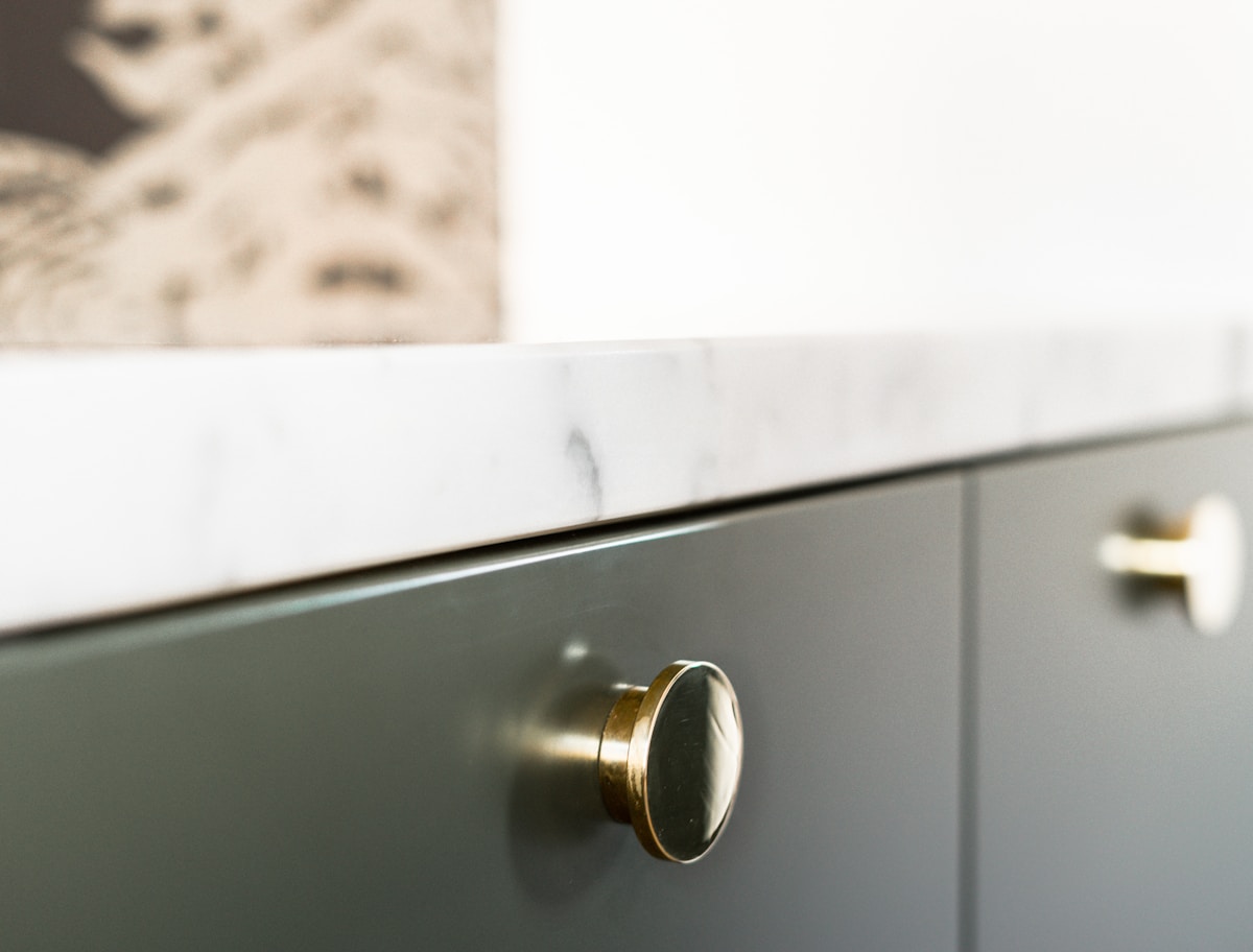 A cast brass knob on a painted drawer front under a marble worktop